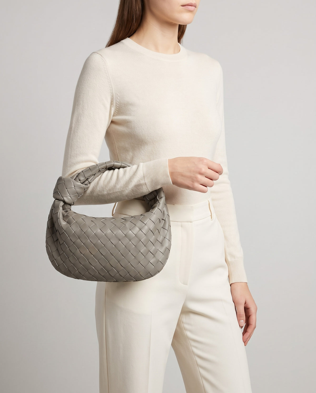 Knot Small woven leather bag in Stone – model carrying it by the knotted handle