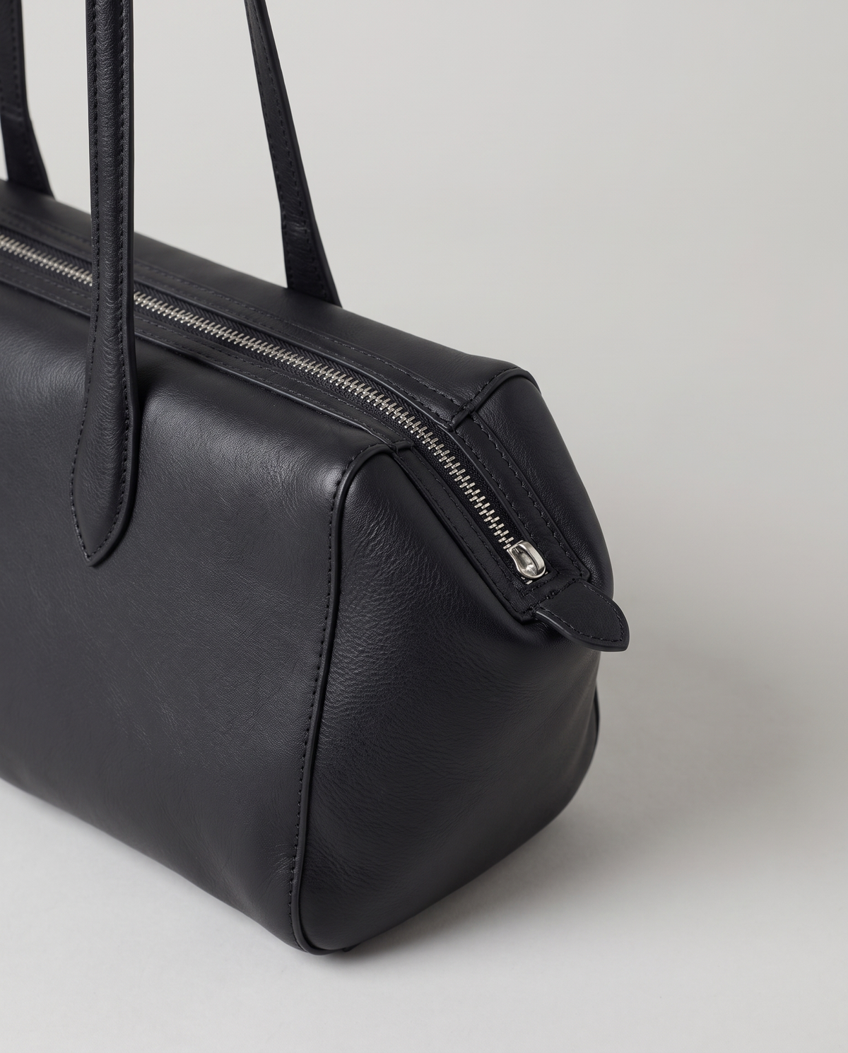 Lira leather shoulder bag in Black – close-up of the zip and strap join