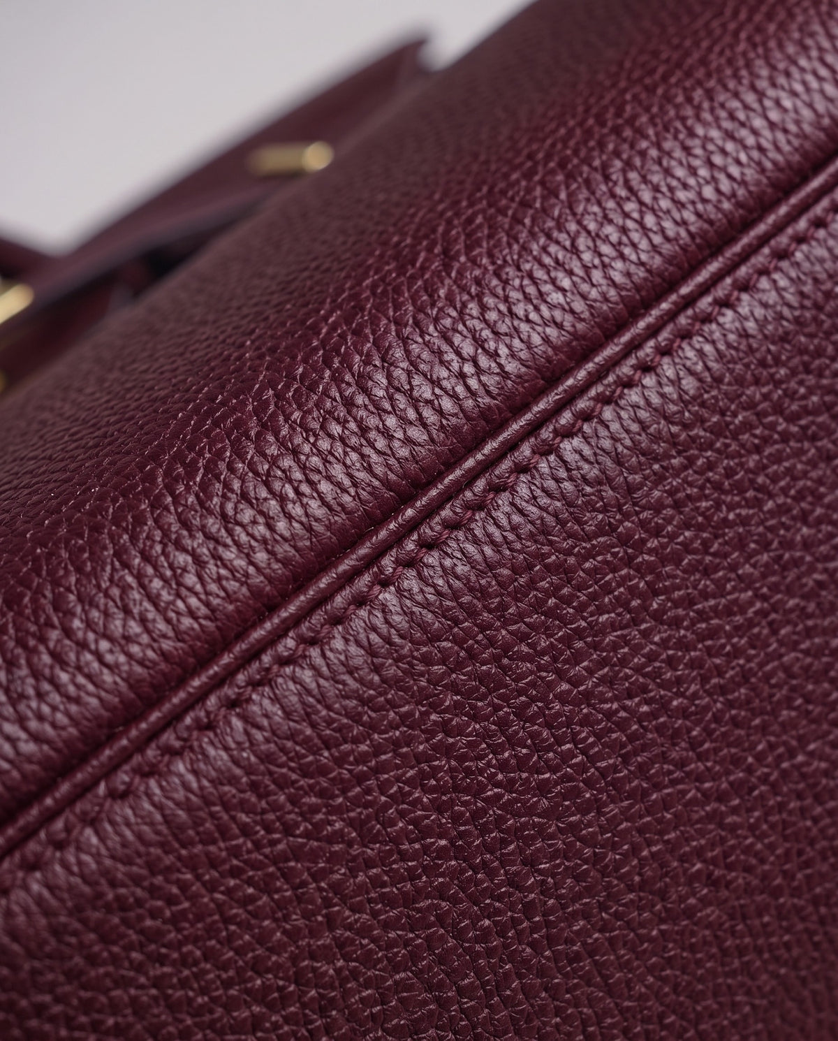 Lock Medium leather top-handle bag in Bordeaux – close-up of the pebbled leather and stitching