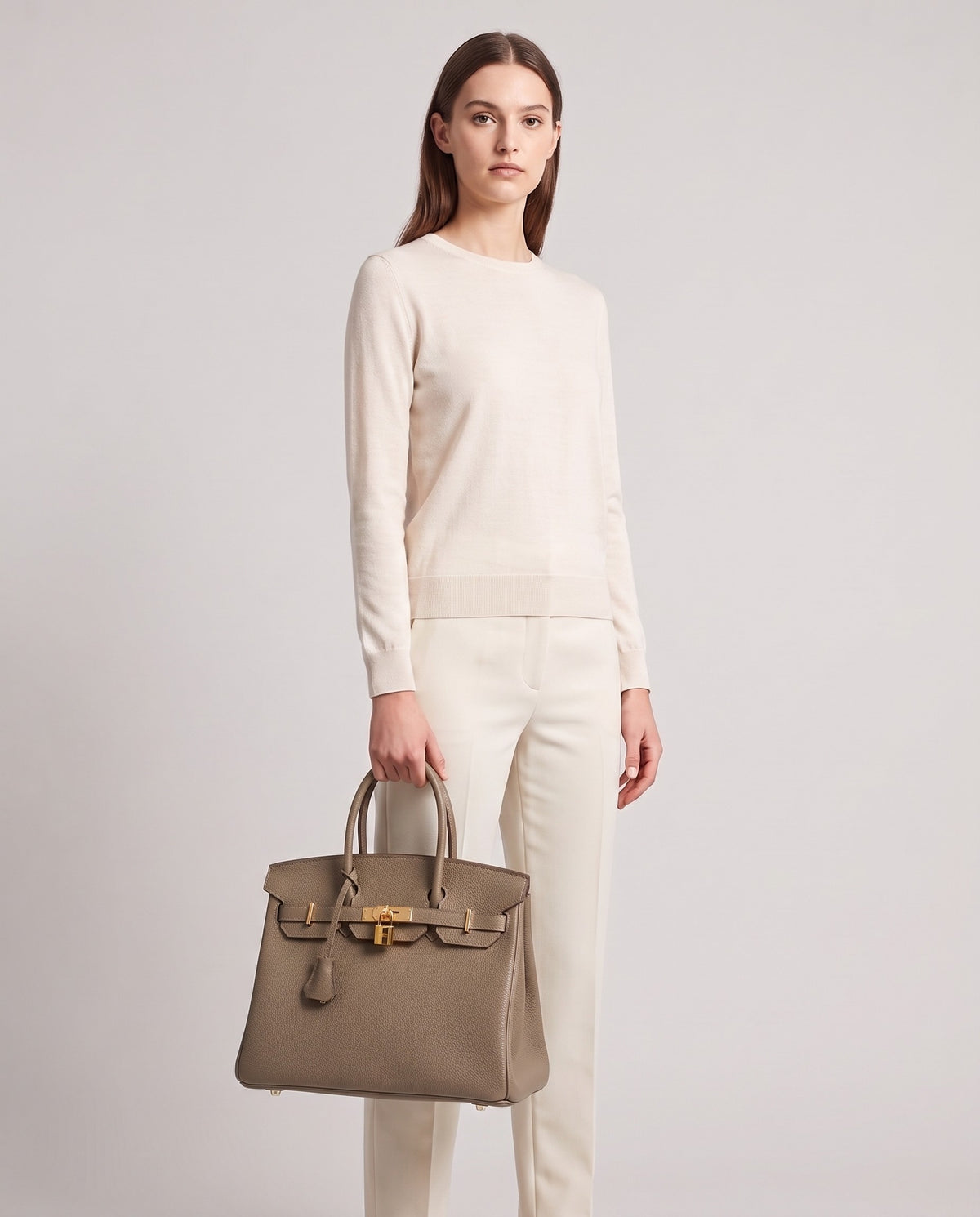 Lock Medium leather top-handle bag in Taupe – model holding it, full length