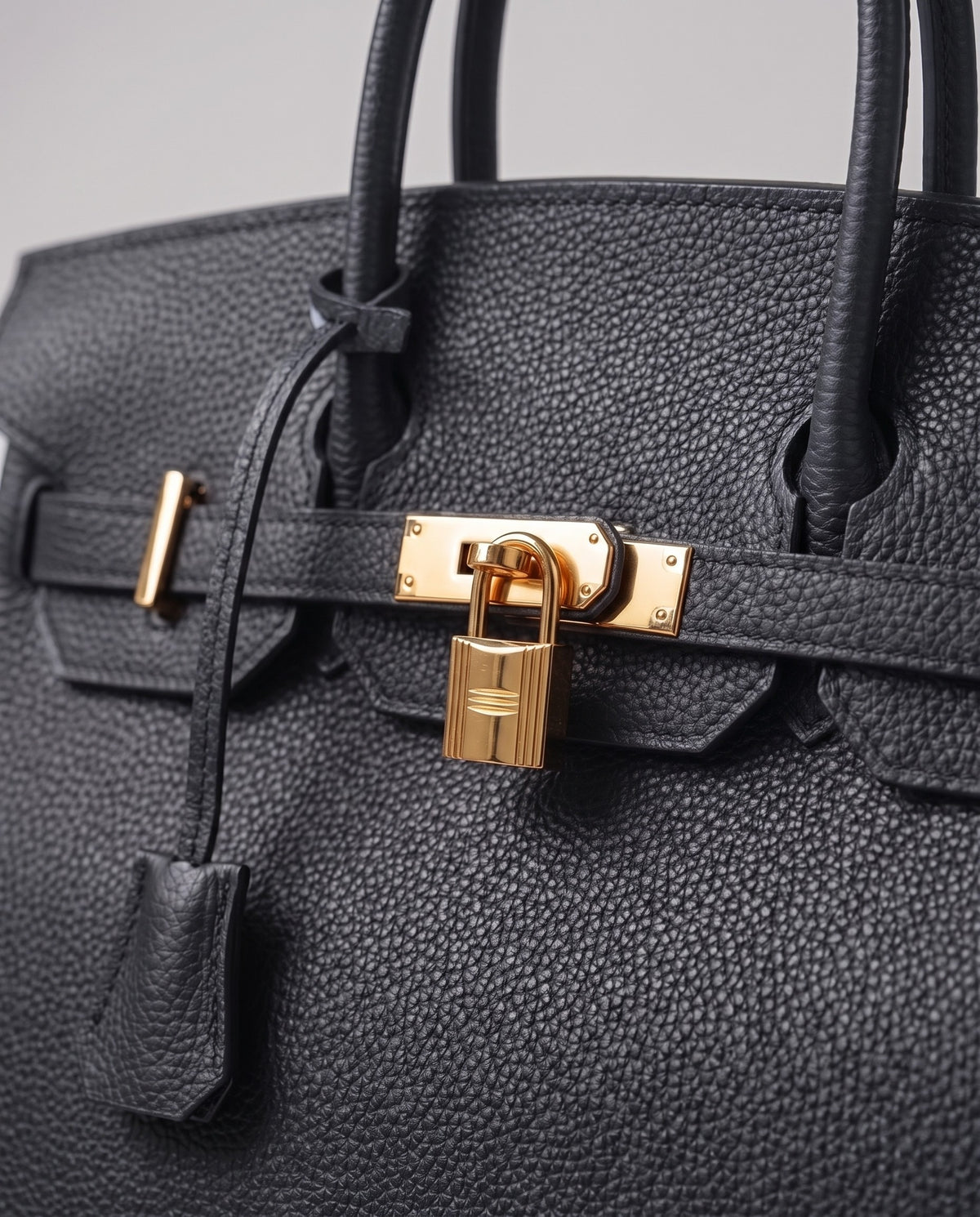 Lock Small leather top-handle bag in Charcoal – close-up of the gold turn-lock and padlock
