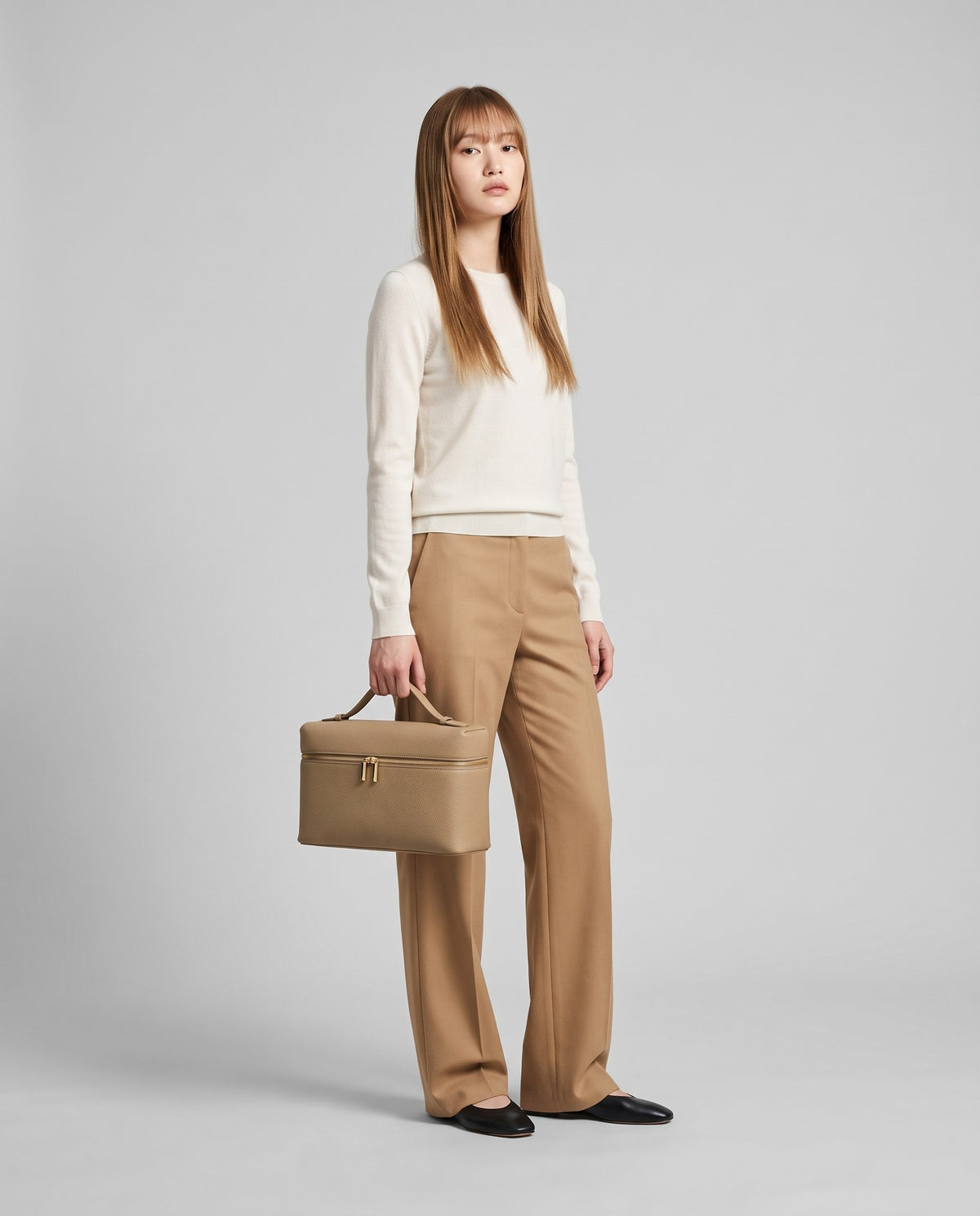 Model holding the Orvieto vanity case in Stone – full-length view