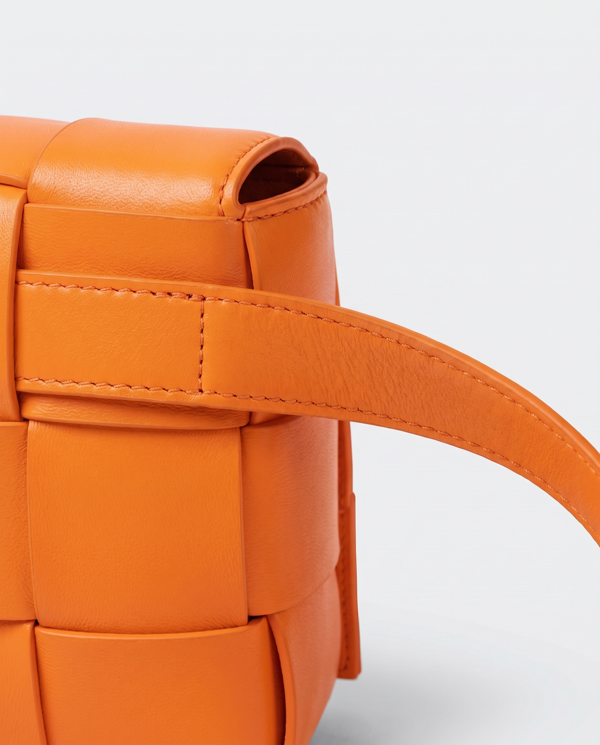 Cassette padded woven leather belt bag in Orange – close-up of the strap attachment