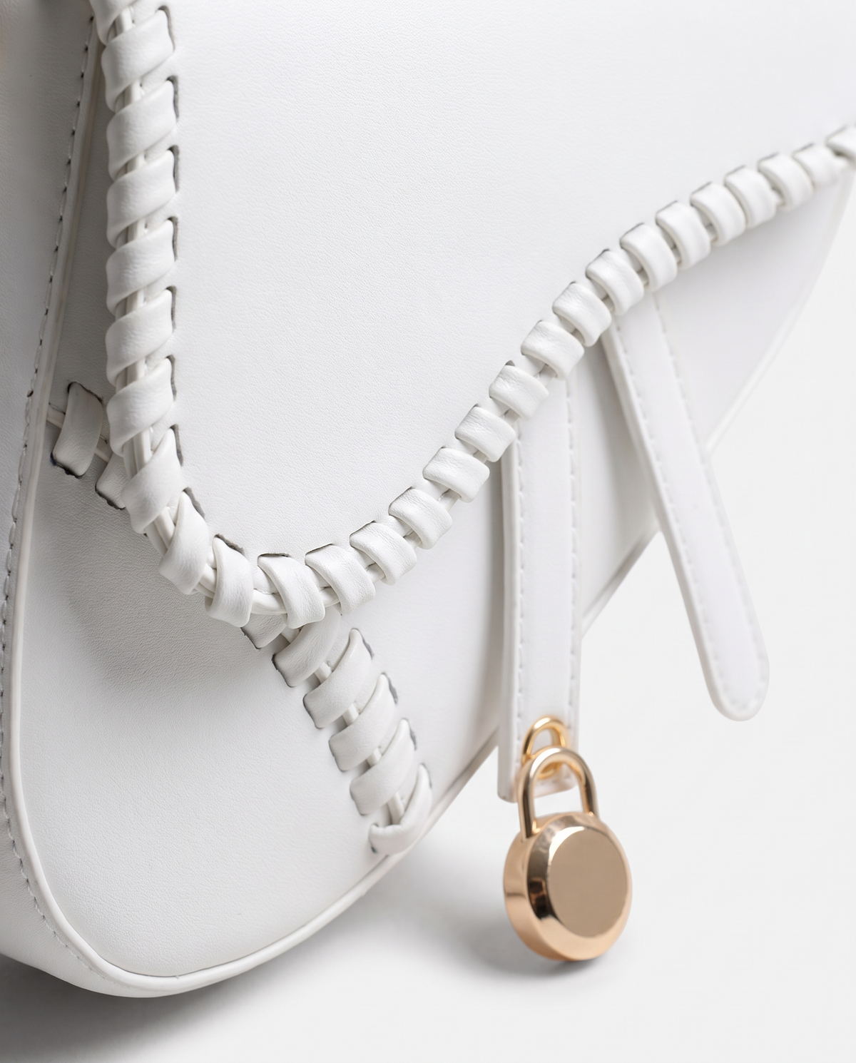 Saddle vegan leather shoulder bag in White – close-up of the whipstitched edge and gold padlock charm