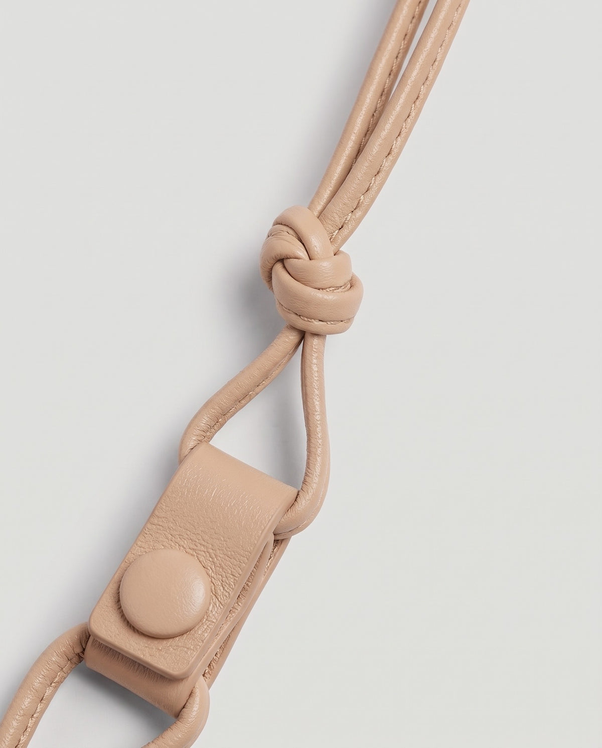 Serata woven leather clutch in Beige – strap knot and snap detail