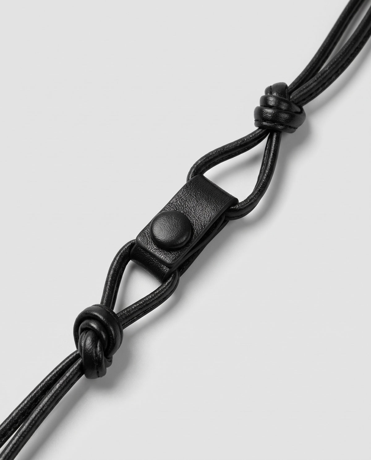 Serata woven leather clutch in black – strap knot and snap detail