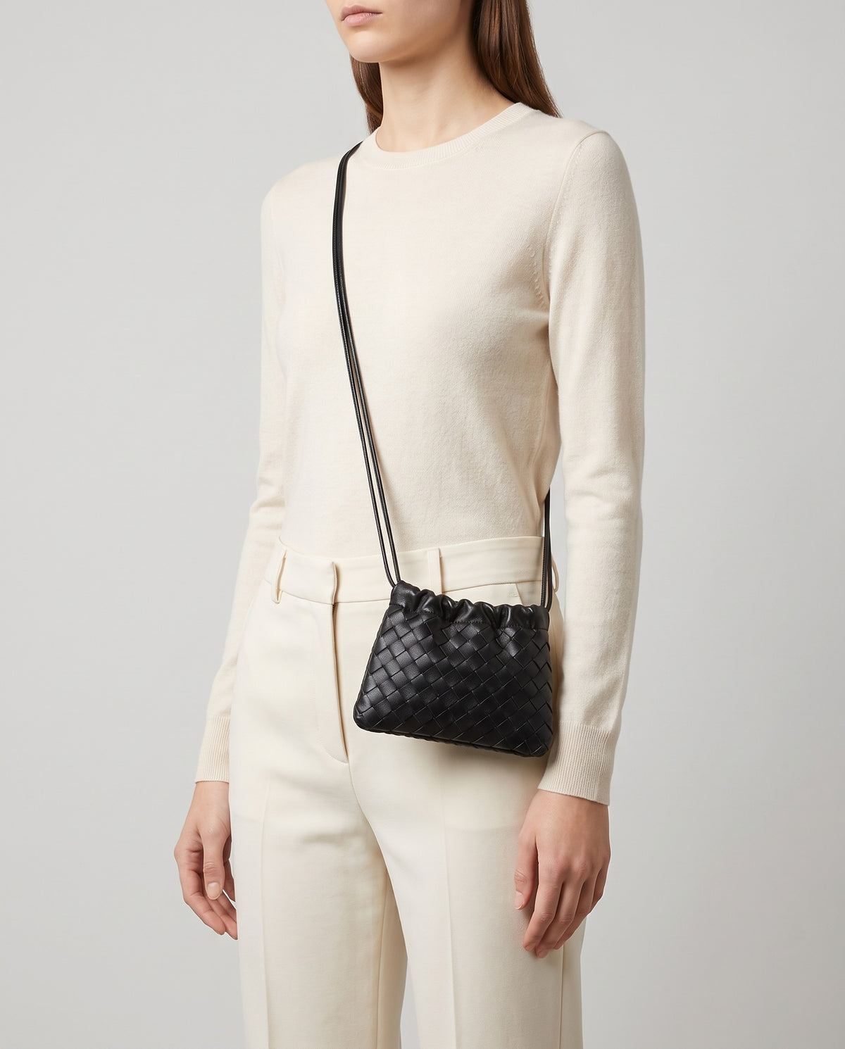 Model wearing the Serata woven leather clutch in black crossbody
