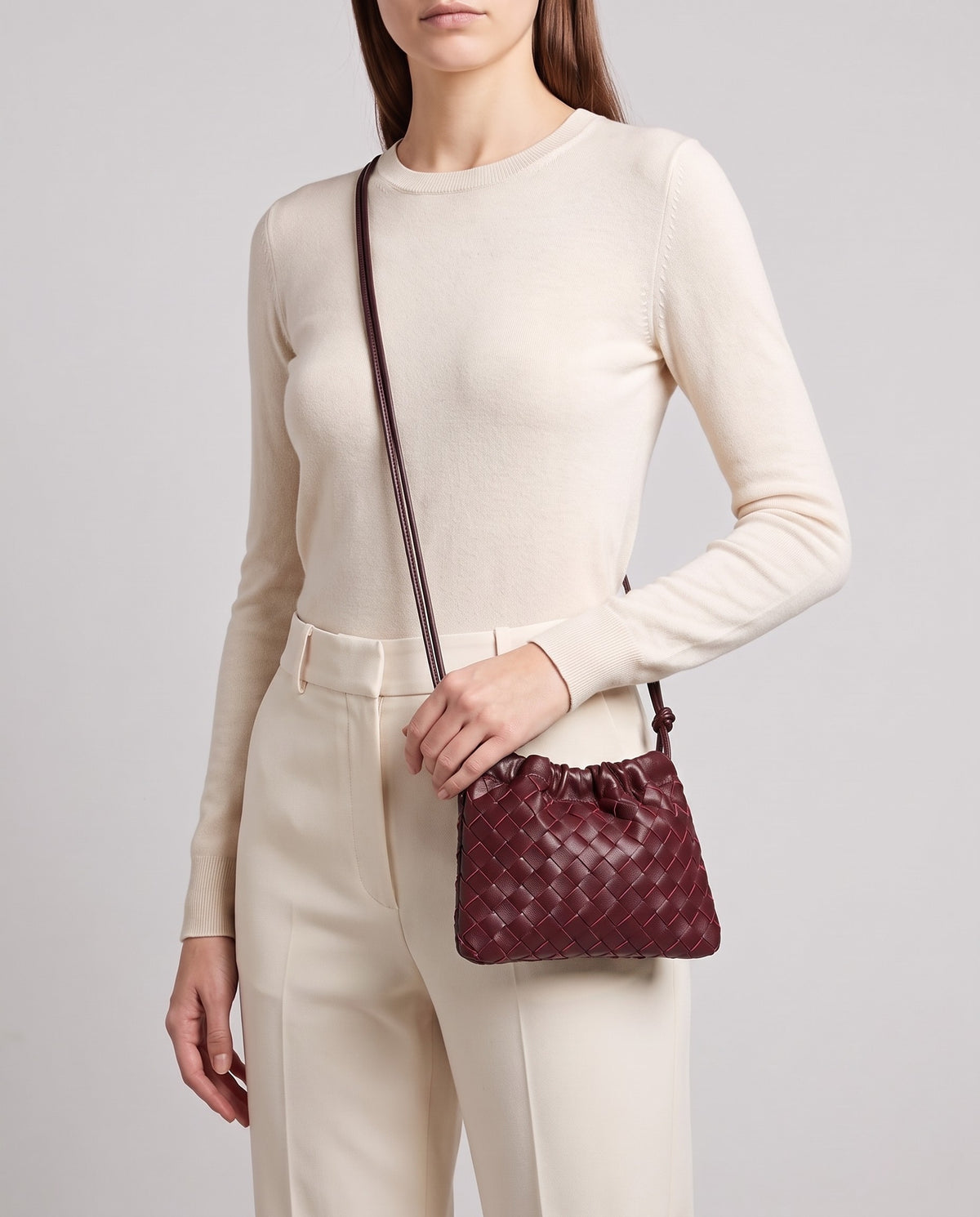 Model wearing the Serata woven leather clutch in Burgundy crossbody