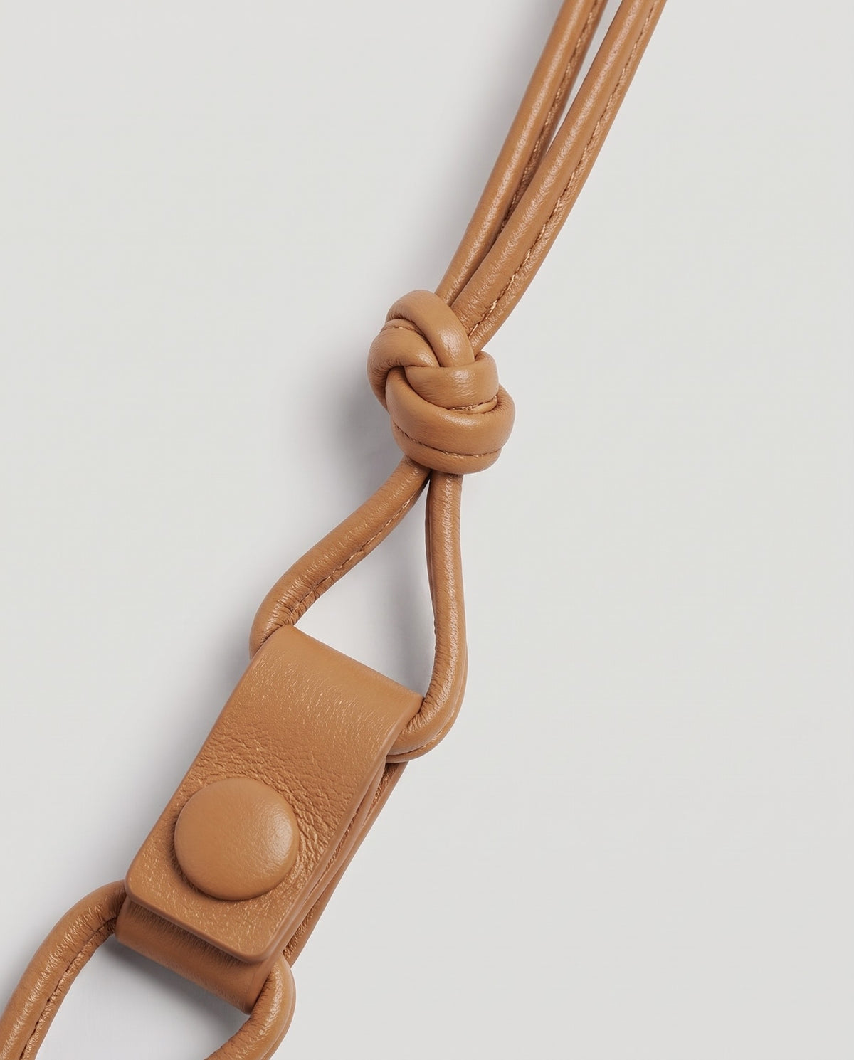 Serata woven leather clutch in Camel – strap knot and snap detail
