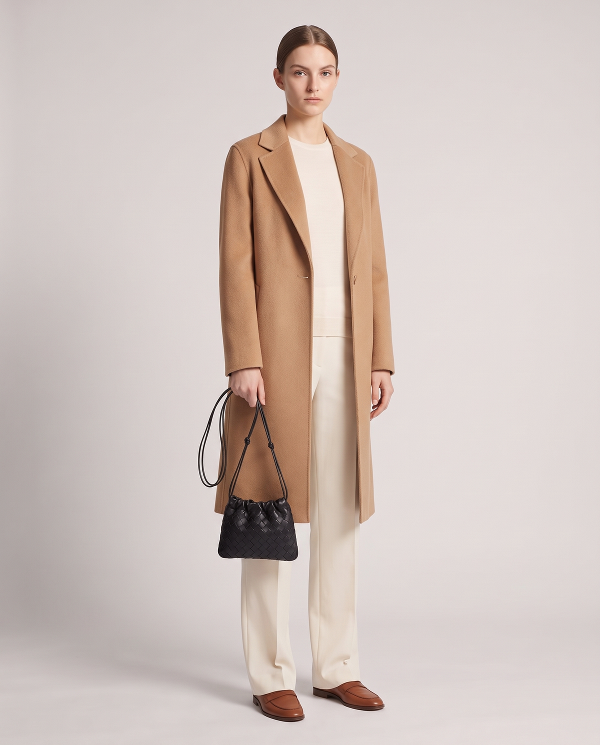 Model holding the Serata woven leather clutch in black – full length