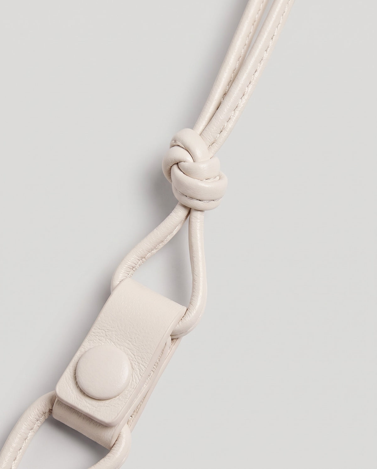 Serata woven leather clutch in Ivory – strap knot and snap detail