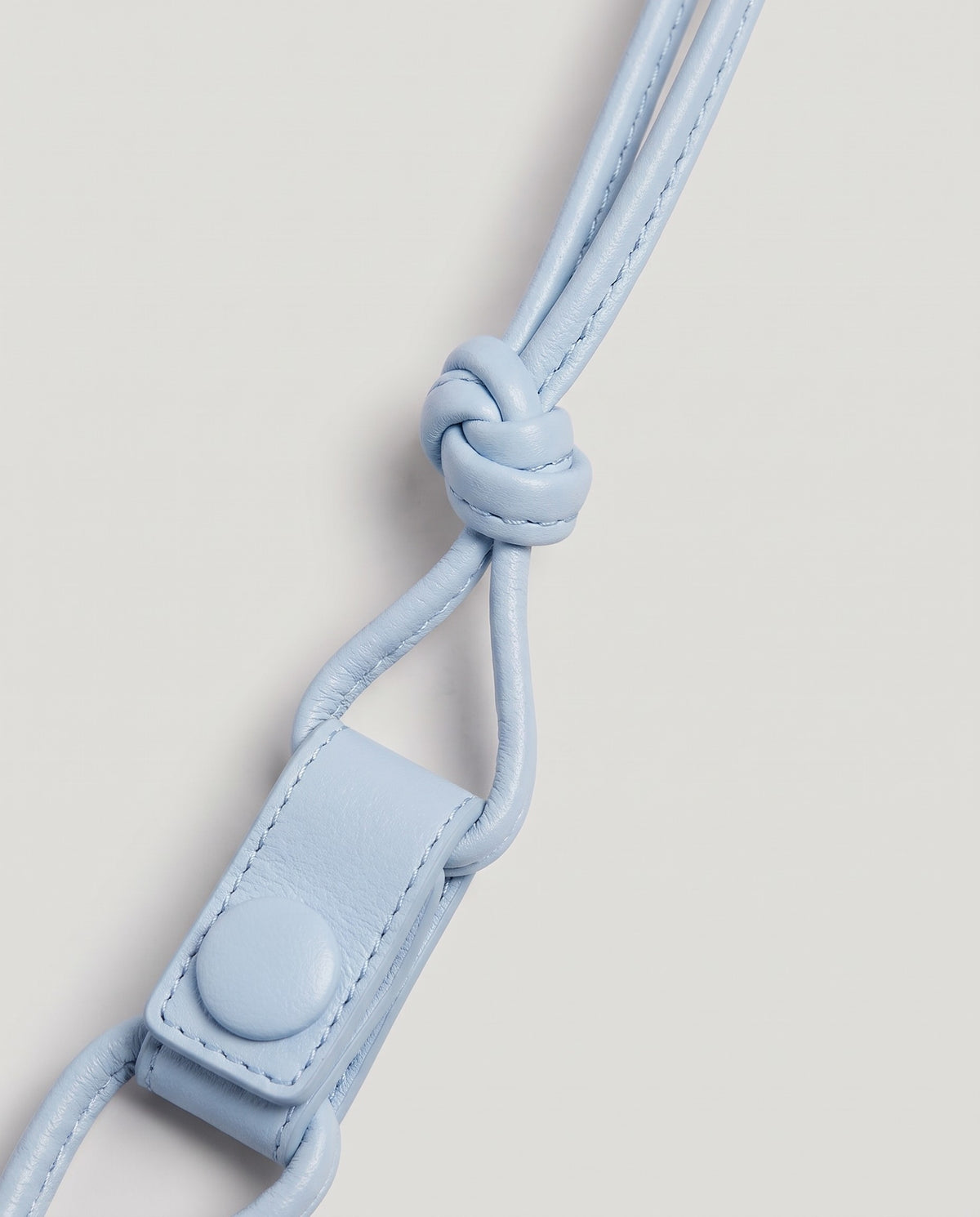 Serata woven leather clutch in Sky – strap knot and snap detail