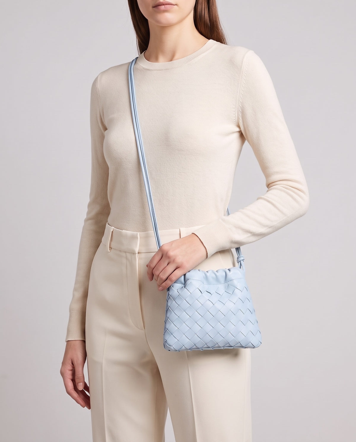 Model wearing the Serata woven leather clutch in Sky crossbody